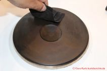 Pflege von alten Gusseisenkochplatten - mit kreisenden Bewegungen die  Platte mit dem Putzling einfärben